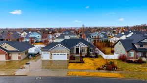 View of front of home with stone siding, a garage, driveway, board and batten siding, and a residential view