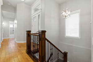 Corridor with an upstairs landing, light wood-style flooring, and a chandelier