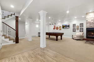 Recreation room featuring a warm lit fireplace, light wood finished floors, pool table, light carpet, and recessed lighting