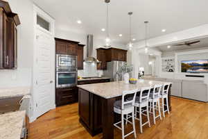 Kitchen featuring a breakfast bar area, open floor plan, dark wood finish cabinets, stainless steel appliances, and a center island
