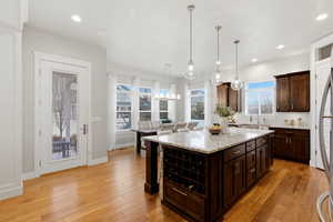 Kitchen with a kitchen breakfast bar, light stone countertops, dark wood finish cabinets, and a kitchen island