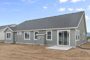 Back of house featuring a patio, a shingled roof, and stucco siding