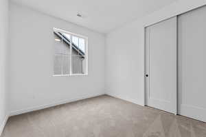 Unfurnished bedroom featuring light colored carpet and a closet