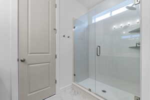 Bathroom with a shower stall and light marble finish flooring