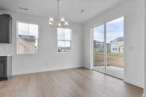 Unfurnished dining area with hanging lights and light wood-type flooring