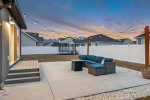 Patio terrace at dusk with a patio area, an outdoor lounge area, a trampoline, and a fenced backyard