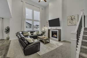 Living room with a high ceiling, a fireplace, and ceiling fan