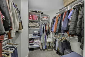Walk in closet featuring light colored carpet