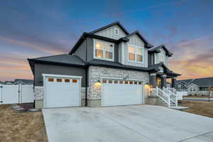 Craftsman-style house featuring a gate, board and batten siding, driveway, stone siding, and an attached garage