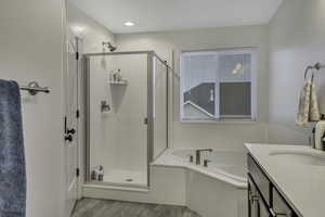 Bathroom with vanity, a stall shower, a garden tub, and light wood-type flooring
