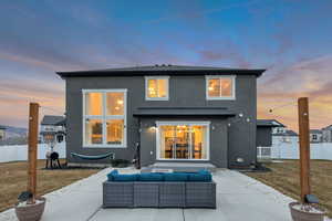 Rear view of property with stucco siding, a patio area, outdoor lounge area, and roof with shingles