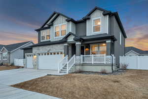 Craftsman inspired home with a garage, a porch, concrete driveway, stone siding, and board and batten siding