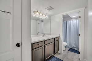 Full bathroom featuring vanity, a textured ceiling, a shower with curtain, and light wood-style floors