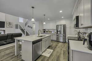 Kitchen with stainless steel appliances, open floor plan, a breakfast bar area, an island with sink, and tasteful backsplash