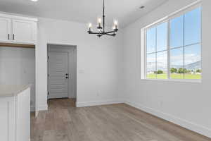 Unfurnished dining area with suspended lighting, a mountain view, and light wood finished floors