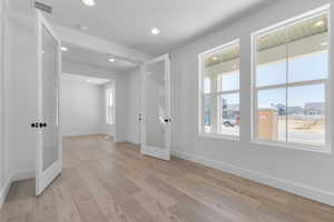 Unfurnished room featuring french doors, light wood-type flooring, and recessed lighting