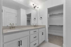 Bathroom with a spacious closet, double vanity, light colored carpet, and light tile patterned floors