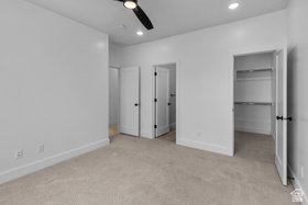 Unfurnished bedroom featuring a spacious closet, light colored carpet, recessed lighting, and a ceiling fan