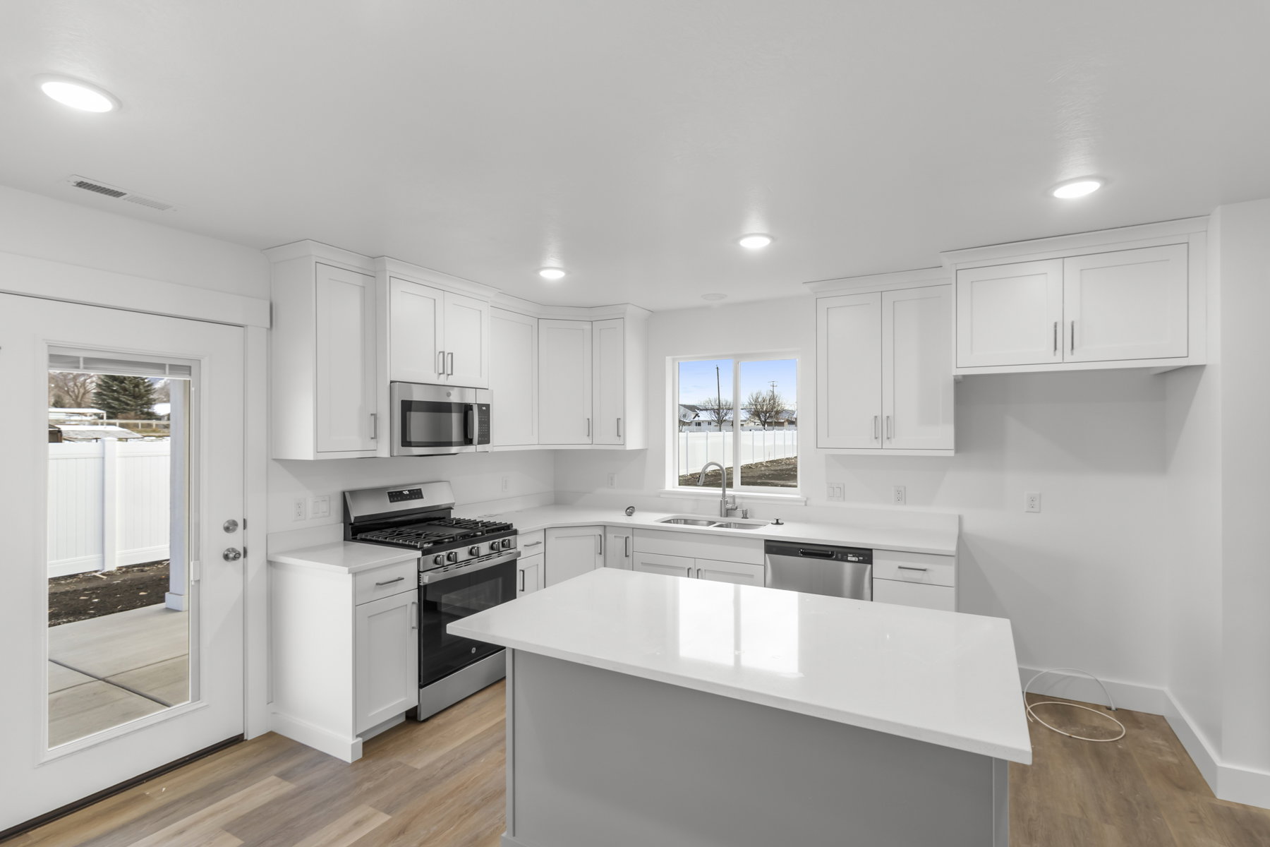 Kitchen featuring stainless steel appliances, white cabinetry, light wood finished floors, a center island, and recessed lighting