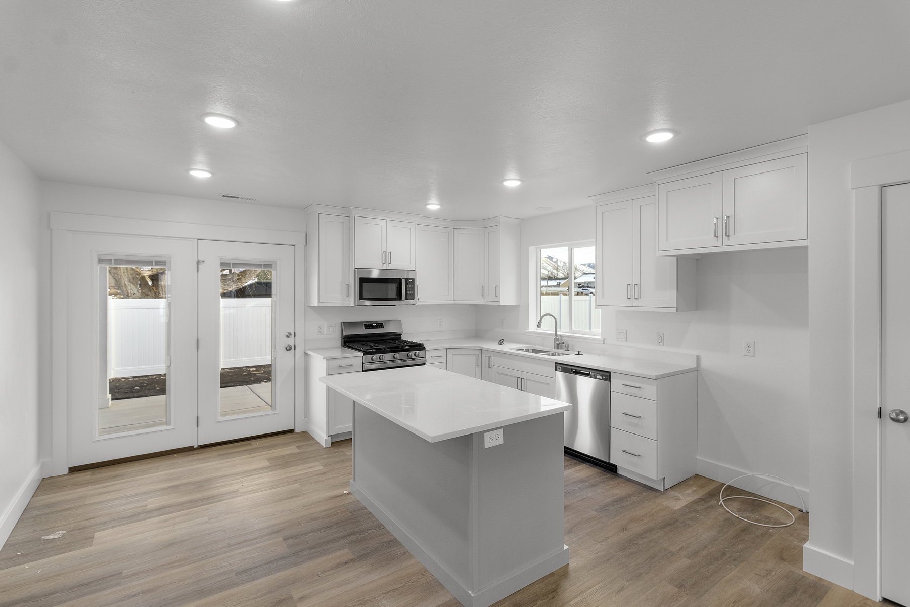 Kitchen with white cabinets, stainless steel appliances, a center island, light wood-style flooring, and recessed lighting