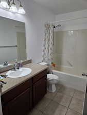 Full bathroom with vanity, shower / tub combo with curtain, and light tile patterned flooring