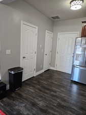 Doors to Half bath, pantry and garage in kitchen, a textured ceiling, and dark wood finished floors