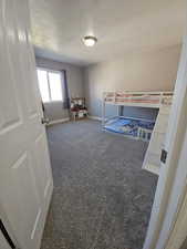 Bedroom featuring a textured ceiling and dark colored carpet