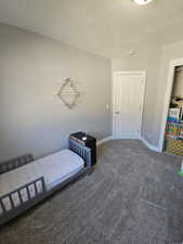 Bedroom featuring dark colored carpet and a textured ceiling