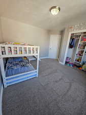 Bedroom with carpet, a textured ceiling, and a closet