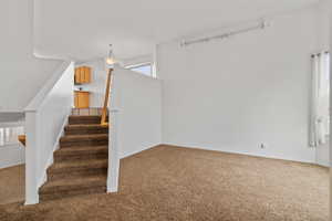Formal living room with high vaulted ceilings and stairs up to the second floor