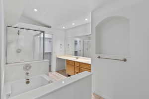 Primary bathroom featuring vanity, tile floors, a separate shower, a soaker tub, and walk-in closet
