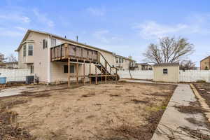 Rear view of house featuring a fenced backyard, and covered patio, a wooden deck off the kitchen, and a storage shed