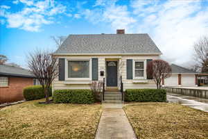 Bungalow with a front lawn, a chimney, and a shingled roof