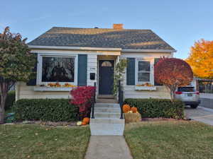 Bungalow-style home with a chimney, a front yard, and roof with shingles