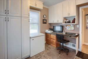 Office space featuring built in study area, crown molding, and light tile patterned floors