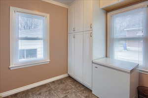 Kitchen featuring white cabinetry, crown molding, light countertops, and plenty of natural light