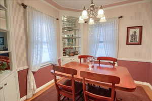 Dining space featuring a chandelier, light wood-type flooring, and crown molding