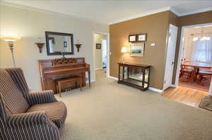 Sitting room with ornamental molding, light carpet, and a chandelier
