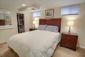 Bedroom with a walk in closet, light colored carpet, and recessed lighting