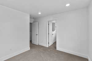 Unfurnished bedroom featuring a spacious closet, recessed lighting, and light carpet