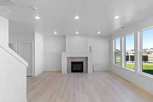Unfurnished living room featuring light wood-type flooring, recessed lighting, and a tiled fireplace