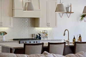 Kitchen with extractor fan, light stone countertops, white cabinets, decorative backsplash, and stainless steel range with gas stovetop