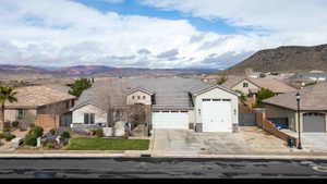 Single story home featuring stone siding, a residential view, an attached garage, stucco siding, and a mountain view