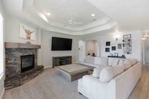 Living room with a stone fireplace, a ceiling fan, arched walkways, and recessed lighting