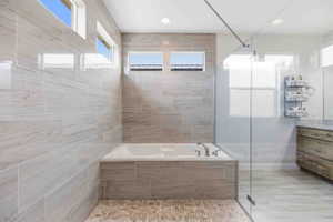 Bathroom featuring vanity, a garden tub, and a tile shower