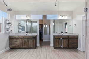 Bathroom featuring two vanities, light wood-style flooring, and a walk in closet