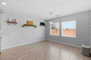 Unfurnished dining area with wood finish floors and a chandelier