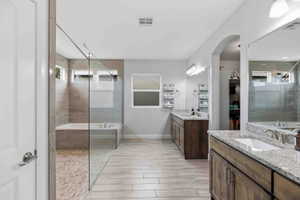 Bathroom with a garden tub, two vanities, tiled shower, and healthy amount of natural light
