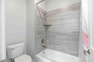 Bathroom with toilet and shower / tub combo with curtain
