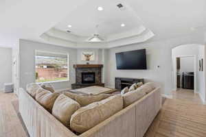 Living room with a fireplace, a ceiling fan, wood finish floors, arched walkways, and recessed lighting